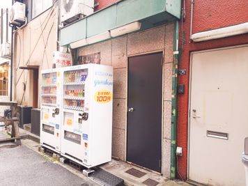 自動販売機の横に黒いドアがあります - KARAOKE DUMMY 元町駅1分！パーティースペースの入口の写真