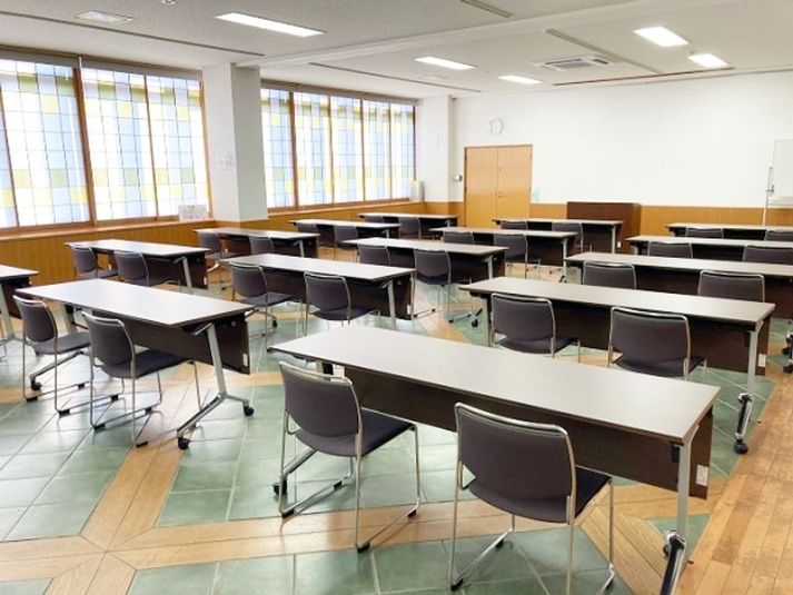 多目的ホールは、二人掛け机15台（横3×縦5）・椅子30脚をセットしたスクール形式でご用意いたします。 - 名古屋会議室 日本陶磁器センター 多目的ホールの室内の写真
